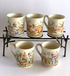 four coffee mugs sitting on a rack in front of a white background