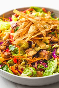 a salad with tortilla chips and lettuce in a white bowl on a table