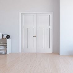 an empty room with two white doors and a shelf on the floor next to it