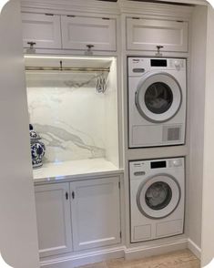 a washer and dryer are in the corner of a room with white cabinets