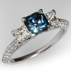 three stone diamond ring with blue and white diamonds on the sides, set in 18k white gold