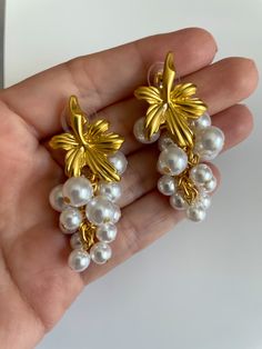 These vintage-style gold plated earrings feature a stunning bunch of pearls that will elevate any outfit, adding a touch of sophistication and elegance. Perfect for any occasion, these earrings are a must-have for anyone seeking to make a statement. Elegant Pearl Charm Chandelier Earrings For Formal Occasions, Elegant Pearl Button Earrings For Formal Occasions, Elegant Formal Chandelier Earrings With Pearl Charm, White Gold Plated Pearl Earrings For Party, Gold Pearl Embellished Chic Earrings, Elegant Gold Pearl Chandelier Earrings, Elegant Party Jewelry With Pearl Buttons, Glamorous Gold Pearl Earrings, Chic Pearl Bridal Earrings For Formal Occasions