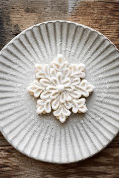 a white plate topped with snow flakes on top of a wooden table