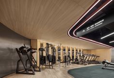 a gym with treadmills and exercise machines in the corner, all lit up by neon lights