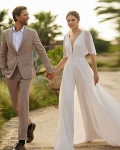 a man and woman walking down a sidewalk holding hands