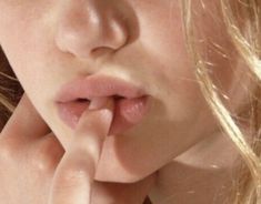 a close up of a person making a hush with their hand near her mouth and finger on the lip