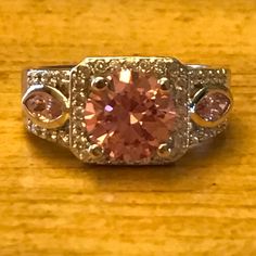 a pink diamond ring sitting on top of a wooden table