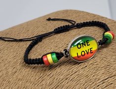 "Rasta Bracelet. One Love Bracelet. Black Braided Bracelet with Rasta wooden beads, Glass Charm with ONE LOVE Design and Rasta Flag Color. Rasta Glass Charm: 1\" Inch x 3/4\" Inch Adjustable Bracelet with sliding knot and cords. Adjust from 6\" Inches up to 10\" Inches Around the Wrist. Fist Most Sizes. Unisex Design The black cord is soft and comfort fit. FAST SHIPPING! Visit my Etsy Shop to see more Handmade Jewelry! At Freedom Lifestyle Jewelry you will find a variety of Necklaces, Bracelets Adjustable Nickel-free Black Charm Bracelet, Nickel-free Black Charm Bracelet As Gift, Nickel-free Black Charm Bracelet For Gift, Nickel-free Black Bracelet Gift, Personalized Black Bohemian Jewelry, Black Bangle Friendship Bracelets As Gift, Black Friendship Bracelets As Gifts, Black Bangle Friendship Bracelets, Black Bangle Friendship Bracelet Gift