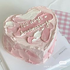 a pink heart shaped cake sitting on top of a table