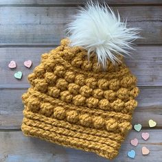 a crocheted beanie with a white fluffy pom - pom on top