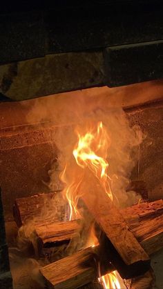 a fire burning in a fireplace with lots of wood and flames coming out of it