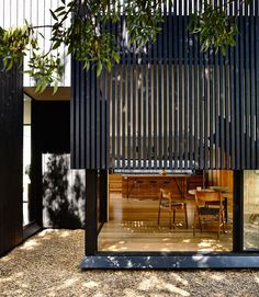 an image of a house that is made out of black slats and has wooden floors