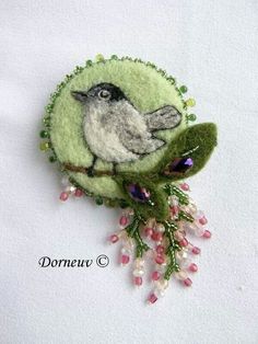 a brooch with a bird sitting on top of it's head and surrounded by beads