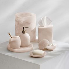 bathroom accessories including soap, toothbrush holder and soap dispenser on white surface