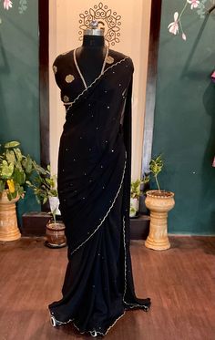 Beautiful black chinnon sari with  all over sequins and scalloped edges with an elegant dola silk brocade blouse saree fabric:chinnon length:5.5 meters blouse: 1m dola silk brocade black petticoat included Size: please choose a standard size from the drop down or you can choose custom measurements.  I'll send you a detailed measurements chart once you order. Pre-draped Saree With Mirror Work For Celebration, Festive Black Pre-draped Saree With Cutdana, Elegant Black Pre-draped Saree With Mirror Work, Black Pre-draped Saree With Resham Embroidery, Black Pre-draped Saree With Pallu For Festive Occasions, Black Georgette Pre-draped Saree With Resham Embroidery, Fitted Pre-draped Chinon Saree With Cutdana, Black Pre-draped Saree For Festivals With Unstitched Blouse, Elegant Pre-draped Saree With Dori Work For Festivals