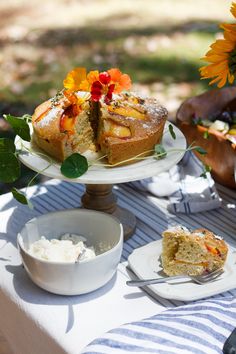 there is a cake on the table with plates and bowls next to it that have flowers in them