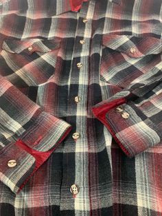 a red and black checkered shirt with buttons on the chest, sitting on a table