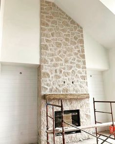 a stone fireplace with scaffolding around it in a room that is being remodeled