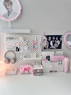 a white desk topped with lots of pink items and pictures on it's wall