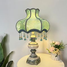 a green lamp sitting on top of a white table next to a potted plant