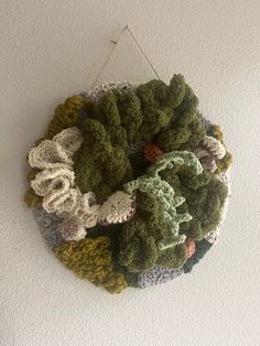 a crocheted wreath hanging on the wall in front of a white painted wall