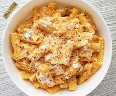 a white bowl filled with pasta covered in parmesan cheese