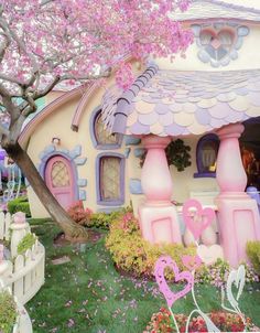 there is a pink and white house in the grass with flowers on it's roof