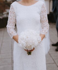 a woman in a white dress holding a bouquet of flowers