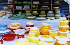 there are many different colored dishes on display at this market table with plates and bowls