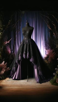 a black dress on display in front of purple curtains