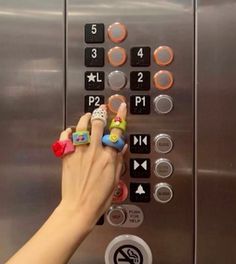 a person pressing buttons on an elevator with their finger rings in front of the button