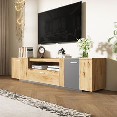 a living room with a large television on top of a wooden entertainment center next to a window