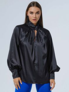 Polished femininity is a key detail in Tia Dorraine's designs, including this alluring blouse, crafted from a lustrous satin fabric in classic black. With an elegantly knotted, high neckline, oversized silhouette, and voluminous sleeves, this day-to-night design will remain a staple in your closet year after year.  Pair it with the Royal Azure Wide-Leg Trousers for an effortlessly elegant look. Hand wash only. Wash inside out with like colours. Do not wring or twist. Do not tumble dry. Iron at 1 Luxury Satin Tops, Luxury Long Sleeve Blouse For Evening, Satin Padded Blouse For Night Out, Luxury Long Sleeve Evening Blouse, Sleek Solid Silk Blouse, Padded Satin Blouse For Night Out, Silk Long Sleeve Blouse For Evening, Glamorous Silk Top For Formal Occasions, Chic Long Sleeve Satin Top