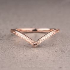 a close up of a gold ring on a gray surface with an arrow design in the middle