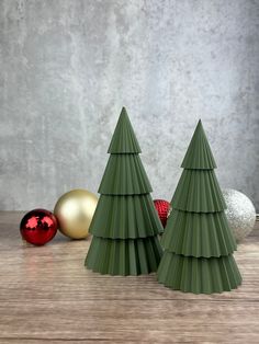 two green christmas trees sitting on top of a wooden table