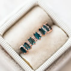 an emerald colored ring sits in a white box