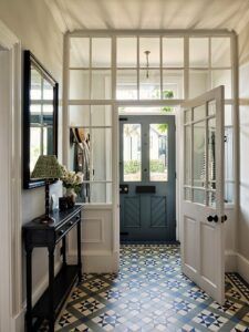 a hallway with tiled floors and white walls, black door and mirror on the wall