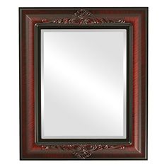 a red and black framed mirror on a white wall with an ornate border around it