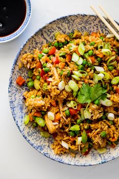 a blue and white plate topped with rice and veggies next to a cup of coffee