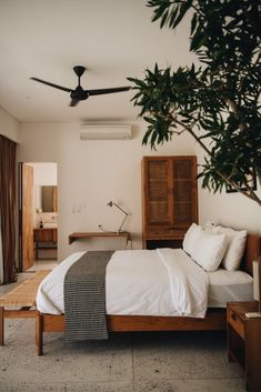 a bedroom with a bed, dresser and ceiling fan