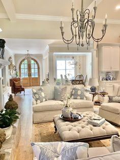 a living room filled with lots of furniture and a chandelier hanging from the ceiling