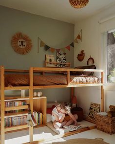 a young child sitting on the floor in front of a bunk bed with bookshelves