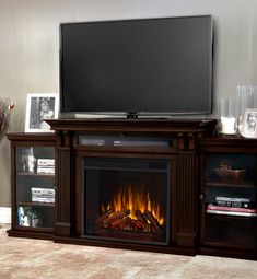 an entertainment center with a fire place and television on the stand, in front of a wall mounted flat screen tv