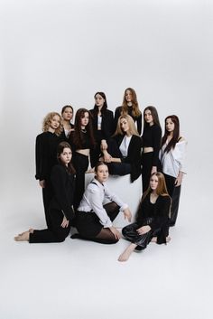 a group of women posing for a photo in front of a white background with one woman sitting on the floor