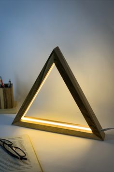 a light that is sitting on top of a table next to a book and glasses