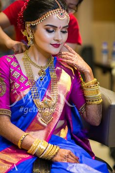 a woman in a blue and pink sari sitting down with her hands on her chin