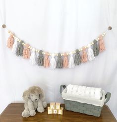 a teddy bear sitting on a table next to a baby crib and blanket with tassels