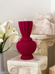 a red vase sitting on top of a white table