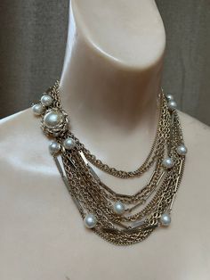 "Wonderful statement necklace for the woman who takes her necklaces seriously.   No name but truly, not needed. Total 12 chains with 2 strands featuring creamy ivory faux pearls about 8mm each. Variety of delicate goldtone chains in different sizes.  Most are a variation of curb links, some textured. Lovely large slide insert clasp to position as you like, perhaps on the side/front of the body.  Clasp measures 1\" diameter. I usually offer coodinating earrings but the ones I have are very large Elegant Multi-strand Pearl Necklace, Elegant Multi-strand Chain Necklace For Wedding, Multi-strand Gold Pearl Chain Jewelry, Gold Multi-strand Pearl Chain Jewelry, Chic Beaded Chain Jewelry For Evening, Elegant Gold-tone Chain Necklace For Evening, Elegant Gold-tone Pearl Jewelry, Chic Evening Jewelry With Beaded Chain, Elegant Double Strand Metal Layered Necklace