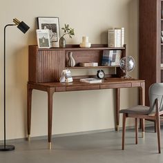 a wooden desk sitting next to a chair in a room with a book shelf on the wall